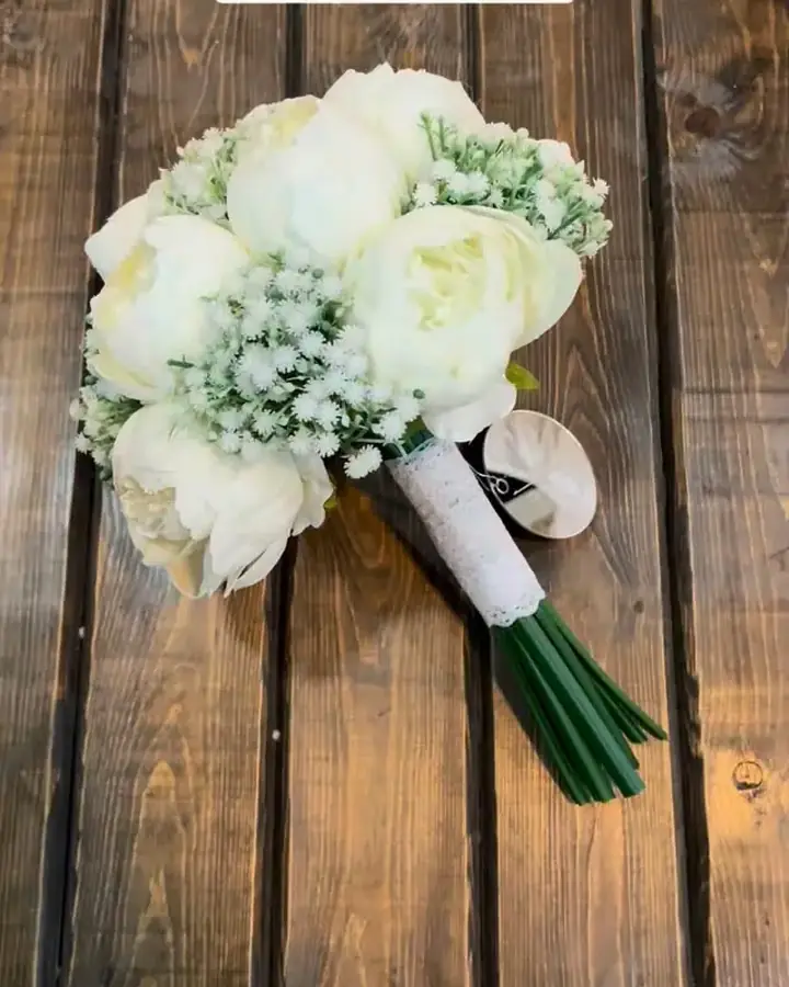 مسكة عروس بيضاء من الورد الصناعي على طاولة خشب — هدايا سلمى